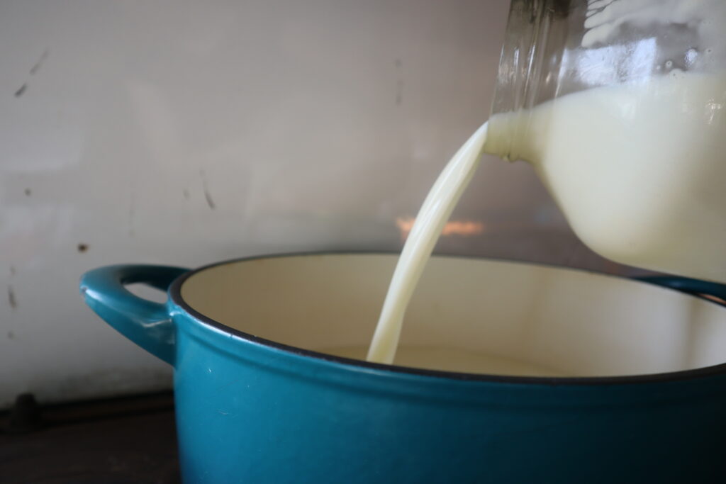 pouring milk from a jar into a dutch oven 