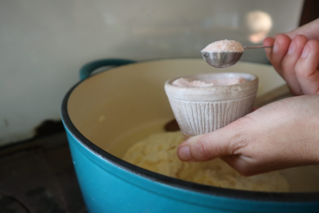 scooping salt from a pinch bowl with a teaspoon 