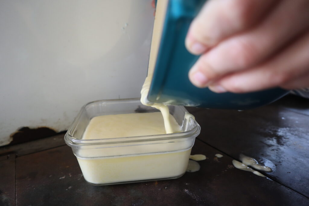 Dumping homemade cheese whiz from a dutch oven into a pyrex bowl 