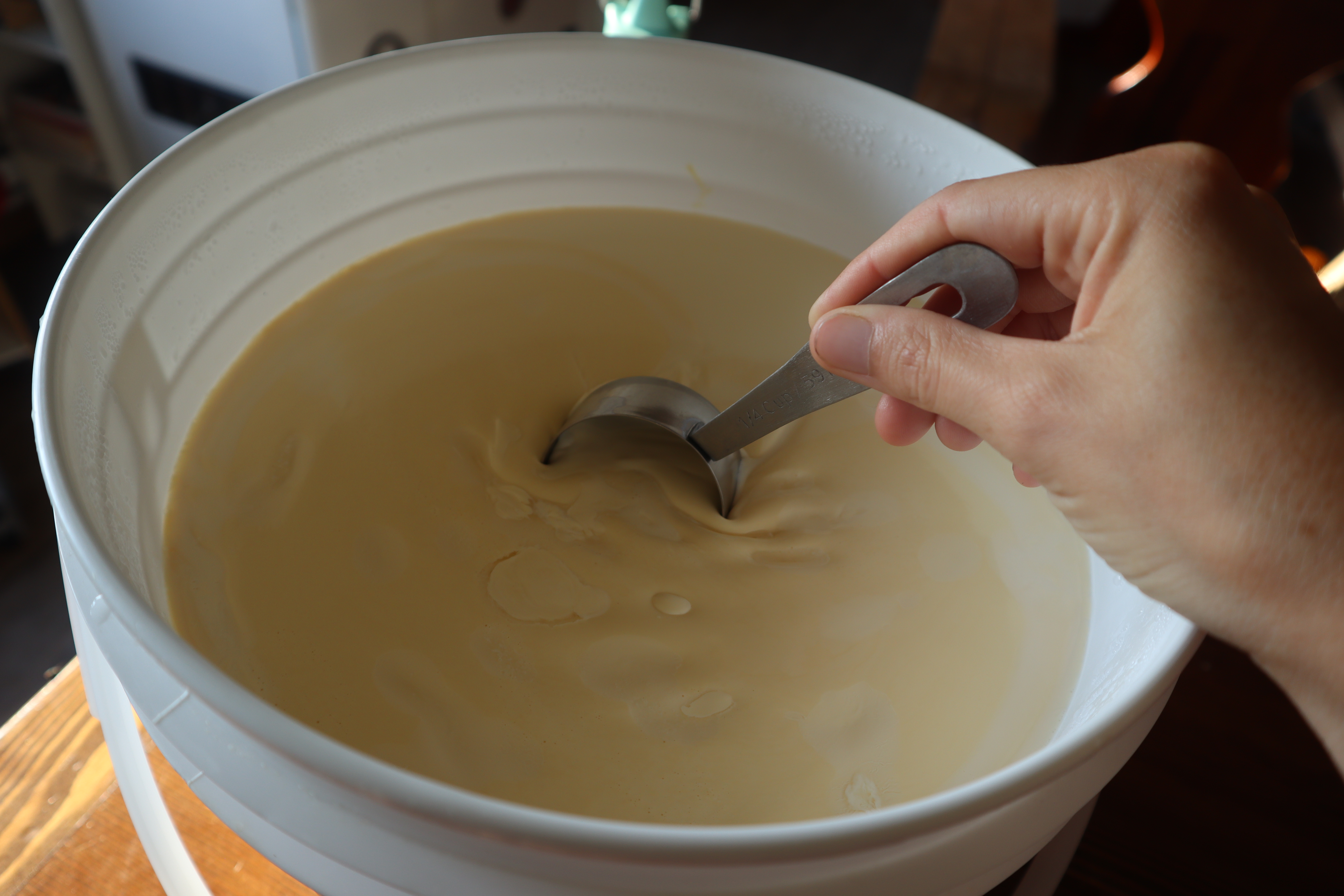 skimming heavy cream off of a bucket of milk 