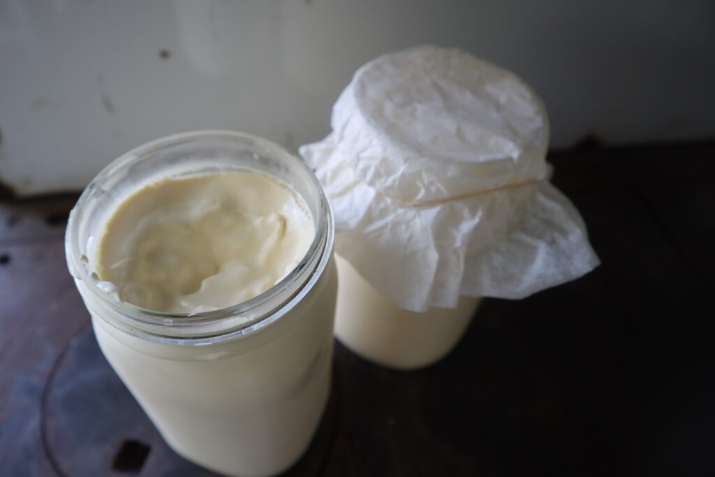 a quart jar of sour cream and a jar covered with a coffee filter