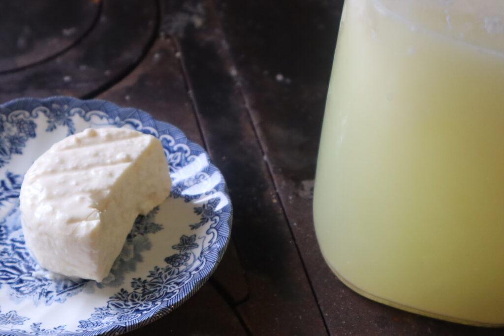 feta cheese on a plate with a jar of whey beside it 
