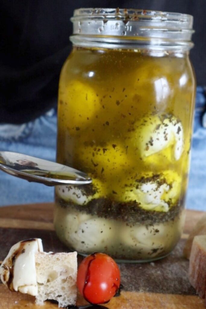 Dipping a spoon into a jar of olive oil marinated cheese
