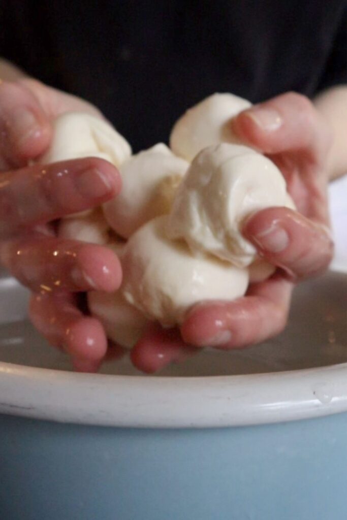 Two hands holding mozzarella balls 
