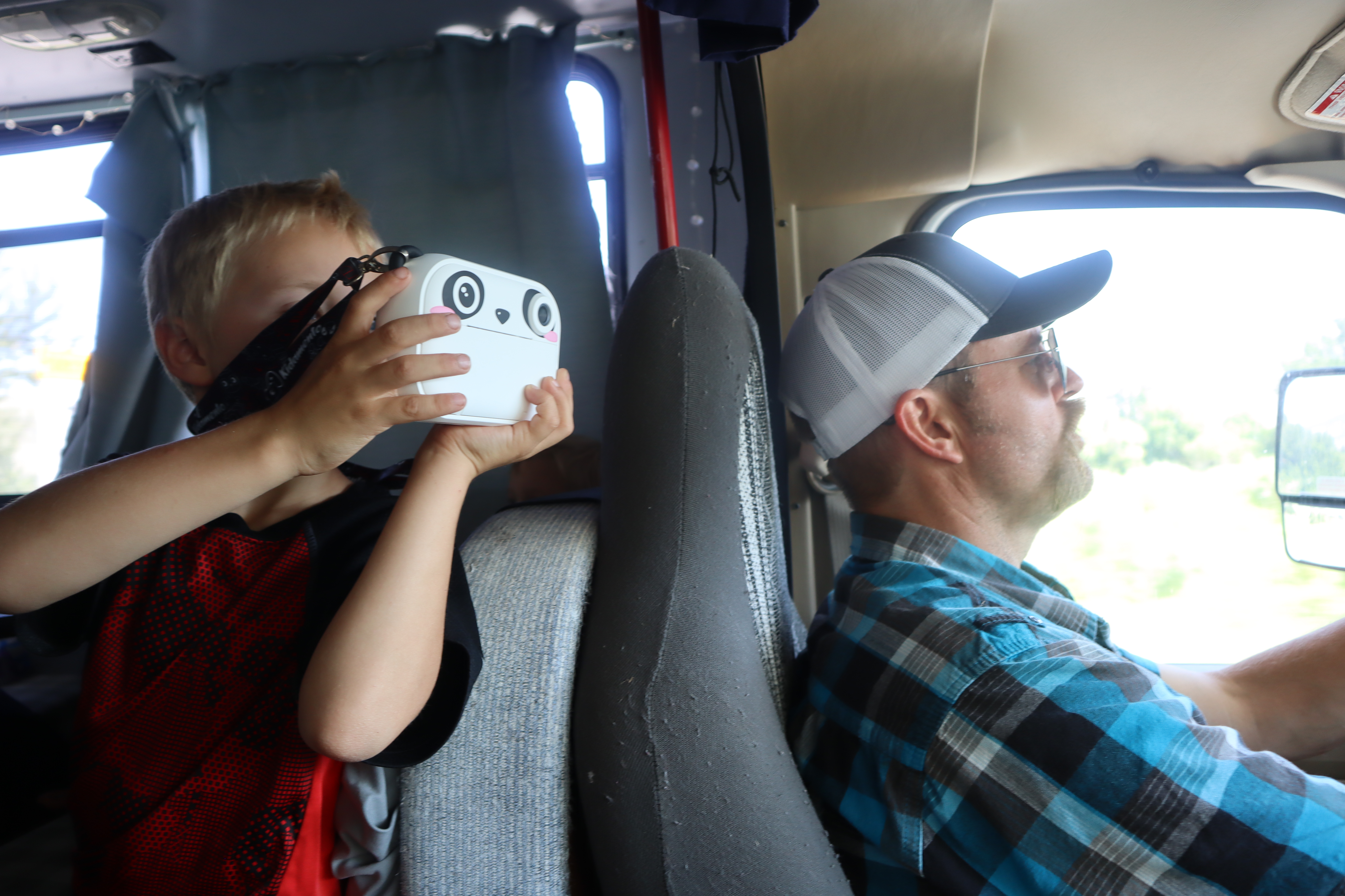 child taking a photo while his dad drives 